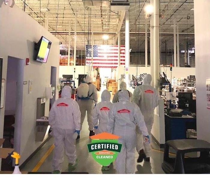 a crew of SERVPRO employees in PPE gear walking inside commercial building
